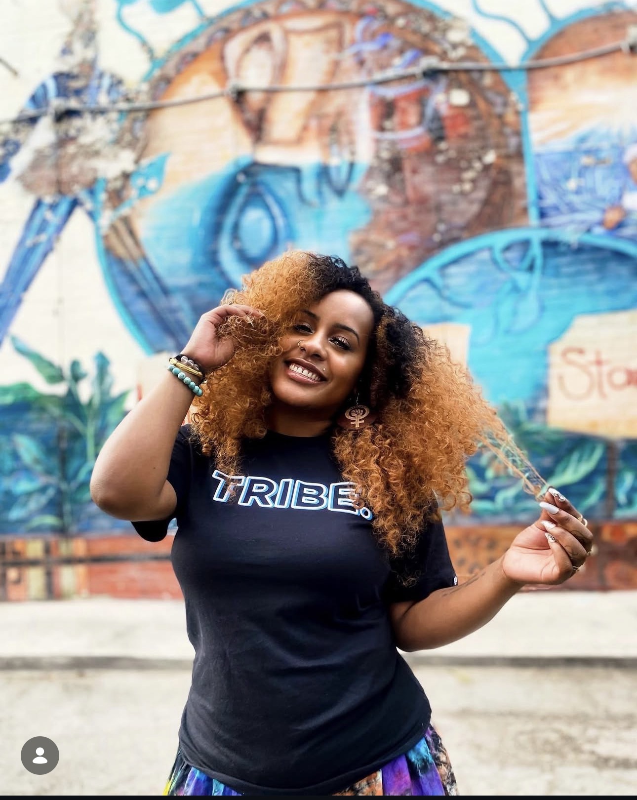 Bobbi Makeda standing in front of a colorful street mural